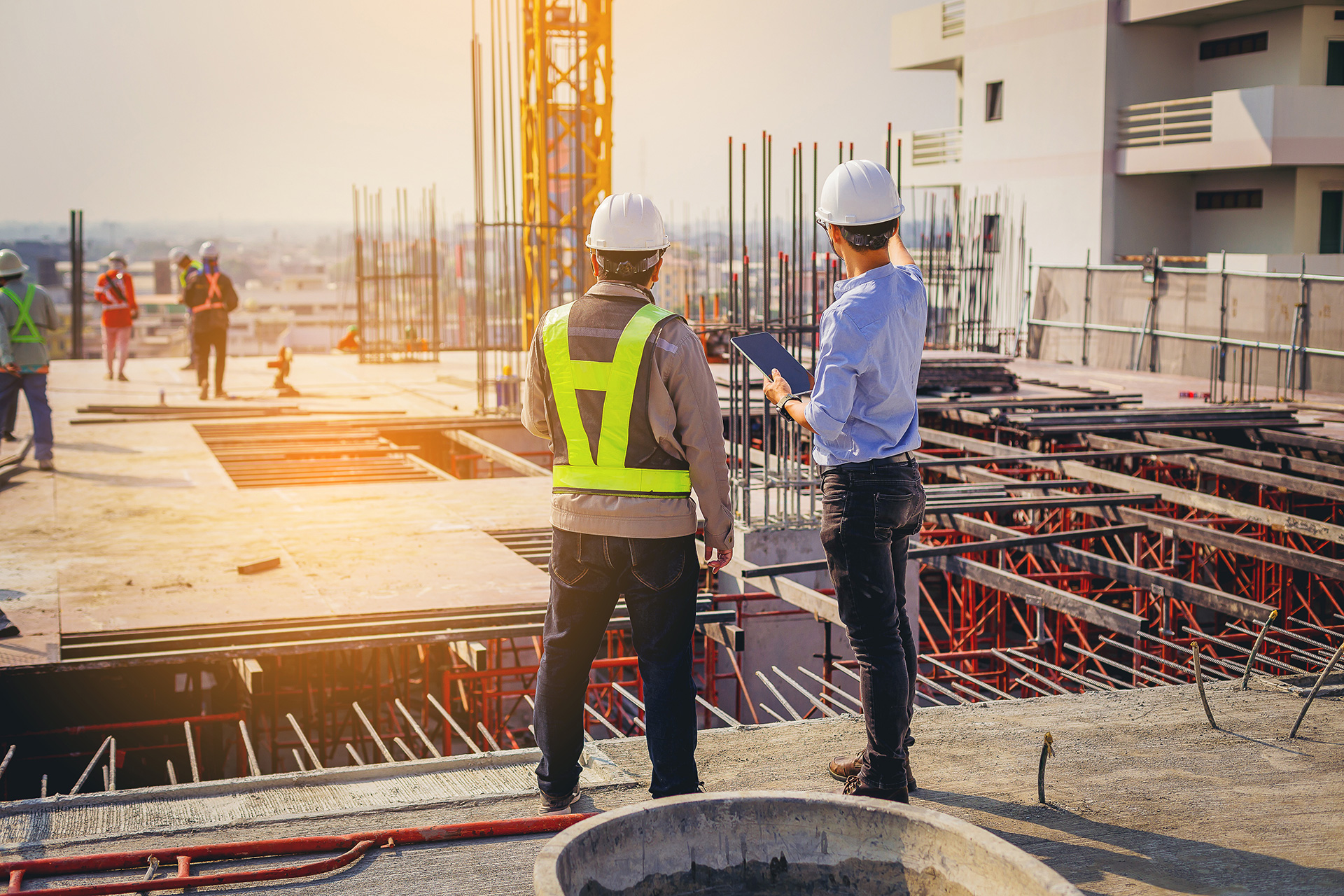 Zwei Sicherheits- und Gesundheitskoordinatoren stehen auf einer Baustelle und besprechen das weitere Vorgehen.